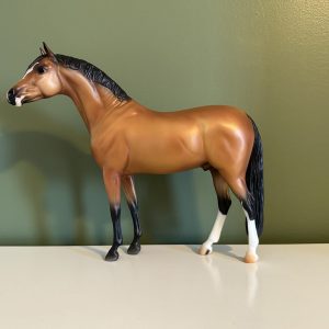 golden buckskin breyer horse with two white stockings on back hind legs and a blaze on face. the model is standing